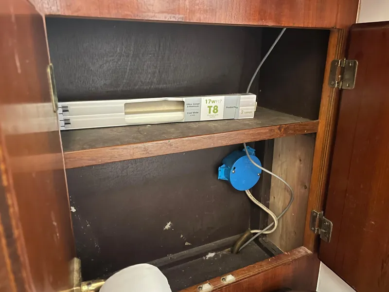 Slide: The Image of Wooden cabinet interior with electrical wiring and a T8 fluorescent light fixture, 1986 Post 43 Sport Fisher. - 44