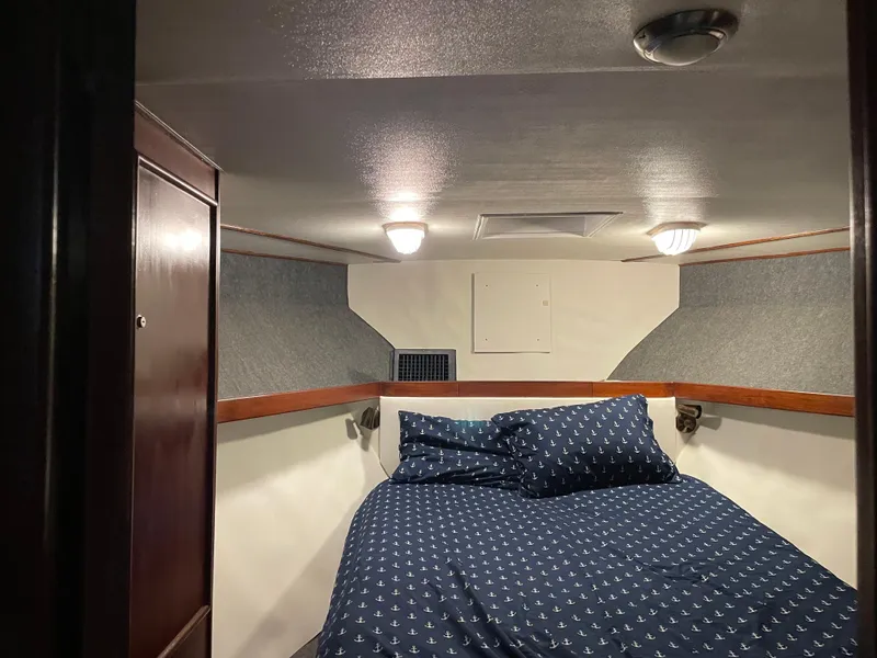 Slide: The Image of 1986 Post 43 Sport Fisher cabin with cozy bed and nautical-themed bedding. - 49