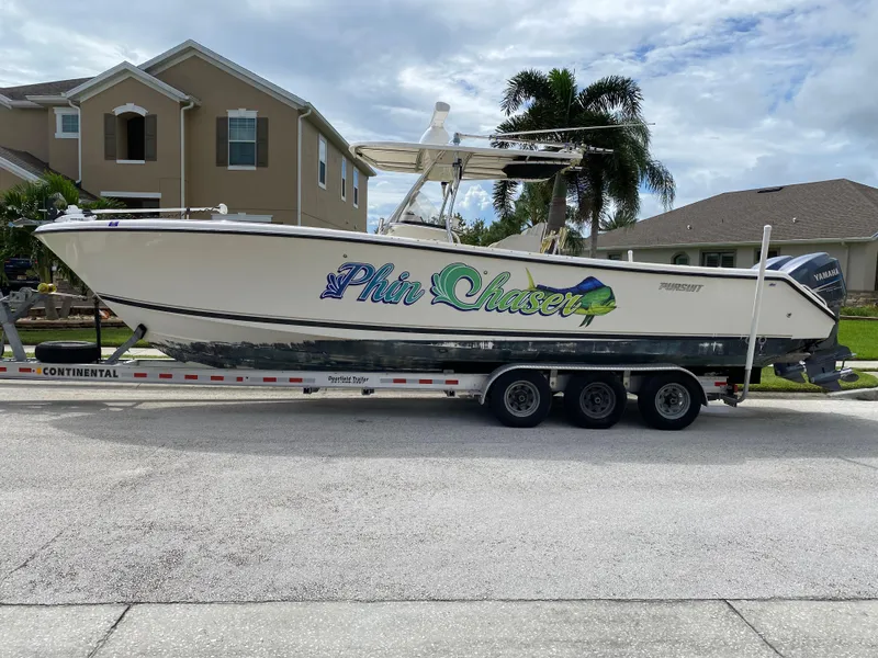 Slide: The Image of 2007 Pursuit 310 Center Console boat on trailer, parked on a sunny street. - 1