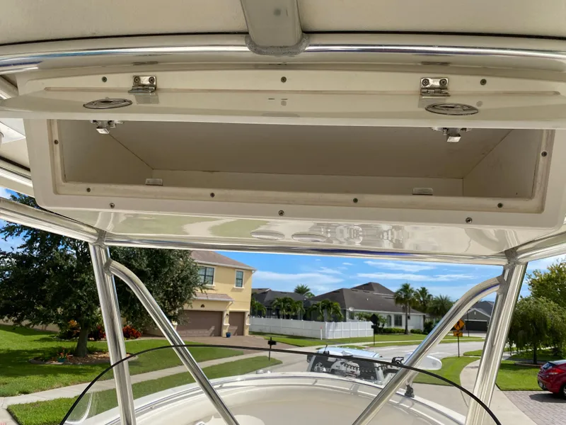Slide: The Image of 2007 Pursuit 310 Center Console boat with open storage compartment, residential neighborhood background. - 24