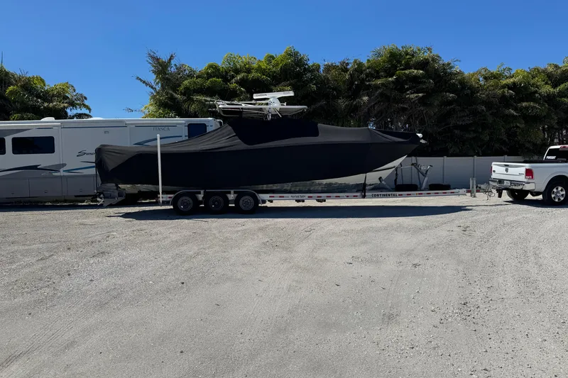 Slide: The Image of 2007 Pursuit 310 Center Console boat covered on trailer, parked beside RV. - 37