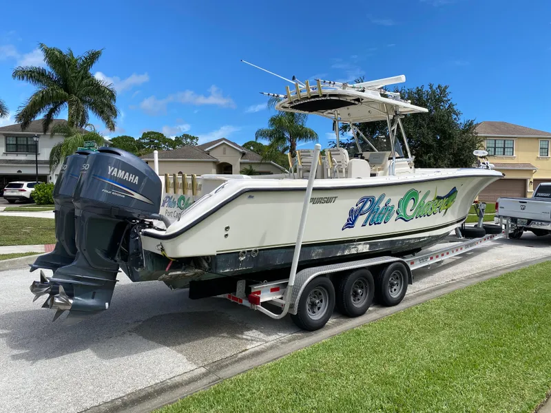 Slide: The Image of 2007 Pursuit 310 Center Console boat on trailer with Yamaha engines, parked in suburban neighborhood. - 6