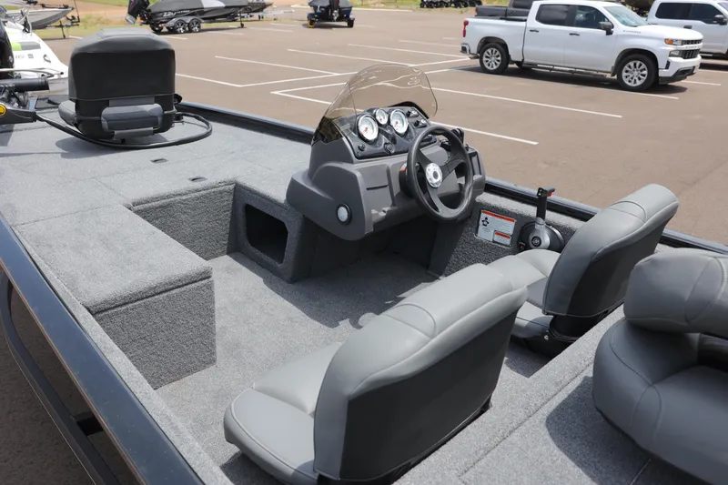 Slide: The Image of 2023 Tracker Pro 170 boat interior with steering console and seating in a parking lot. - 2