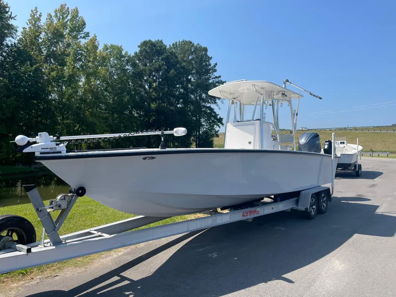 Slide: The Image of 2023 Rambo 27 boat on trailer, parked on road with trees in background. - 1