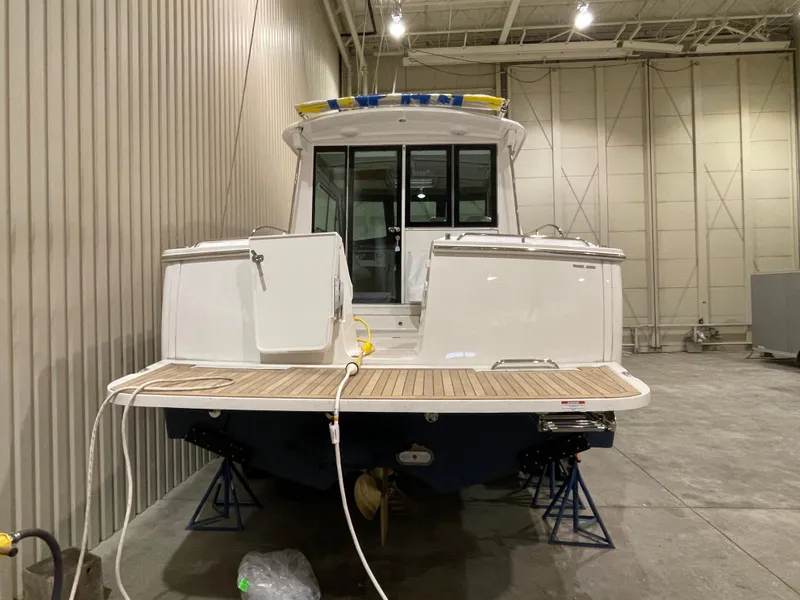 Slide: The Image of 2025 Back Cove 372 boat in a warehouse, rear view with wooden deck. - 10