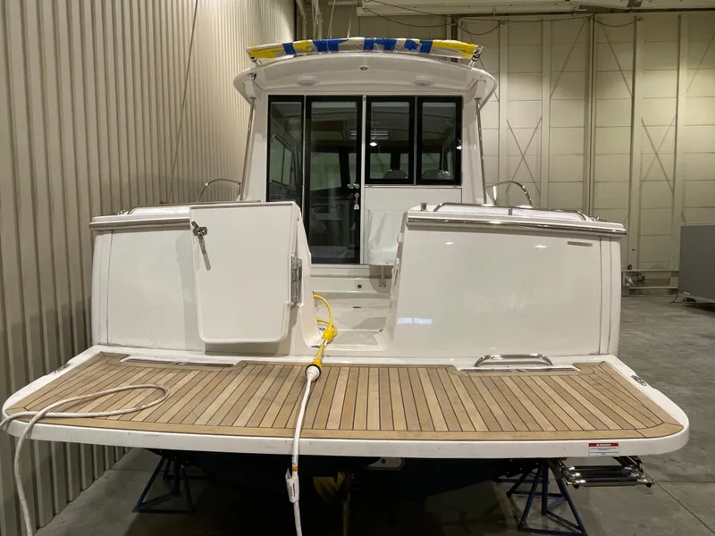 Slide: The Image of 2025 Back Cove 372 boat in a warehouse, featuring a wooden deck and white exterior. - 11