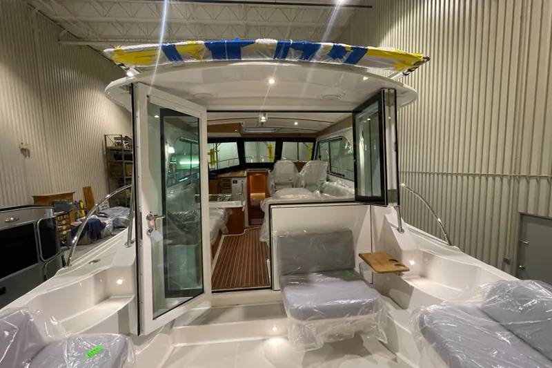 Slide: The Image of 2025 Back Cove 372 yacht interior with seating, covered in protective plastic, in a showroom. - 15