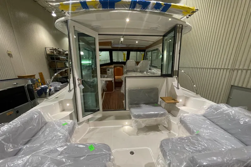 Slide: The Image of 2025 Back Cove 372 boat interior with seating and open doors in a showroom. - 16