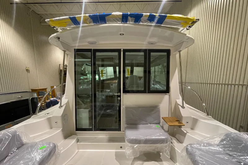 Slide: The Image of 2025 Back Cove 372 boat interior with seating and glass doors in a showroom. - 17