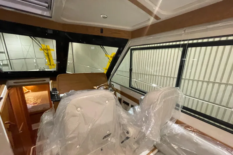 Slide: The Image of 2025 Back Cove 372 interior with helm seats, wrapped in protective plastic. - 31