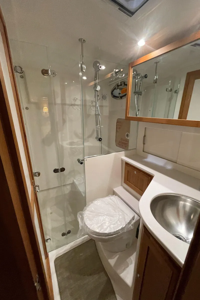 Slide: The Image of 2025 Back Cove 372 yacht bathroom with glass shower, sink, and wooden accents. - 46