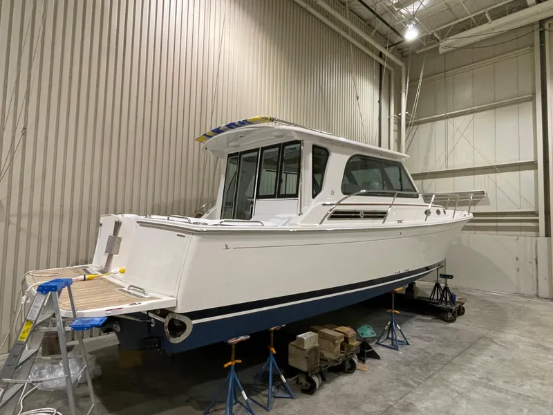 Slide: The Image of 2025 Back Cove 372 boat in storage, white hull, indoor facility, supported on stands. - 7