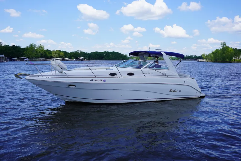 The Image of 2000 Rinker 330 Fiesta Vee boat on a calm lake under a blue sky. - 0