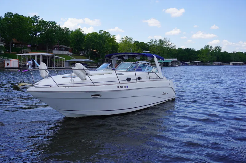 Slide: The Image of 2000 Rinker 330 Fiesta Vee boat on a serene lake with trees in the background. - 3