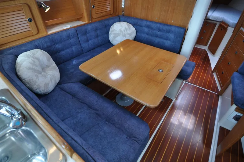 Slide: The Image of 1998 Catalina 36 MkII interior with blue seating, wooden table, and polished floor. - 6