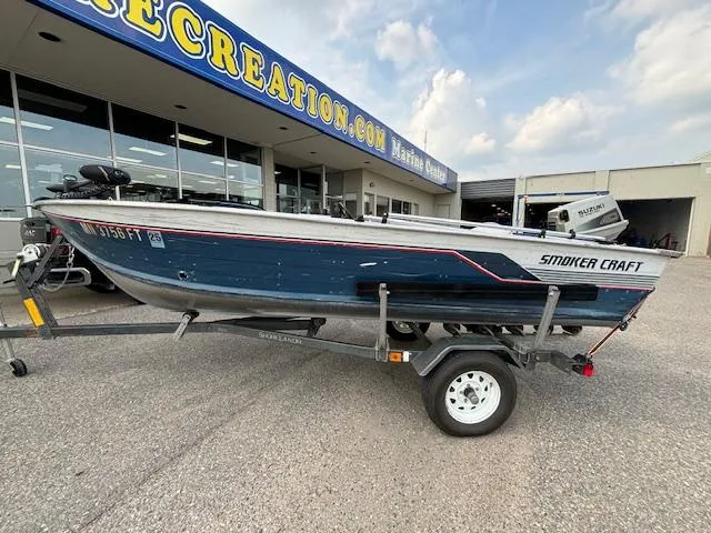 Slide: The Image of 1990 Smoker Craft Resorter boat on trailer outside marine dealership. - 17