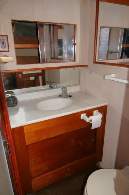 Slide: The Image of 1988 Jersey 36 Convertible Sportfisher cabin interior with striped bedding and wooden cabinetry. - 16