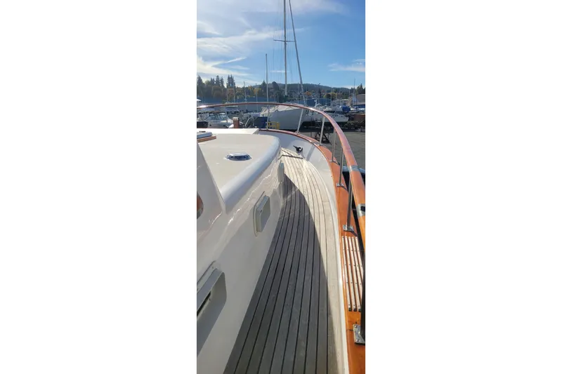 Slide: The Image of 1982 CHB Oceans yacht deck with wooden railings, docked under a clear sky. - 14