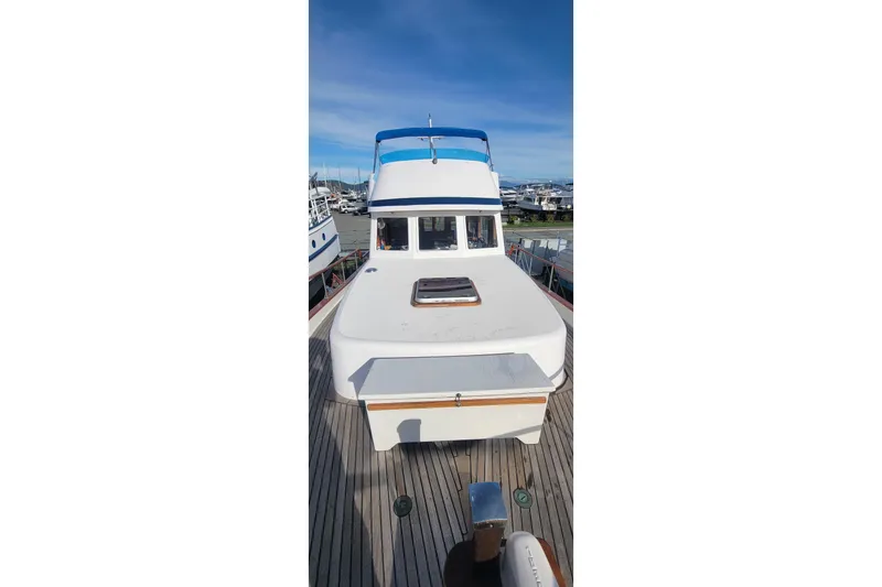 Slide: The Image of 1982 CHB Oceans boat docked, showcasing deck and cabin under clear blue sky. - 23