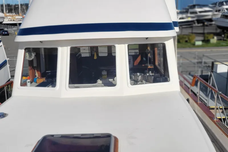 Slide: The Image of 1982 CHB Oceans boat with white exterior and blue trim, docked at a marina. - 31