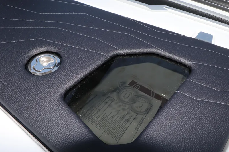 Slide: The Image of 2025 Nautique G25 boat interior detail with sleek black upholstery and visible control panel. - 15