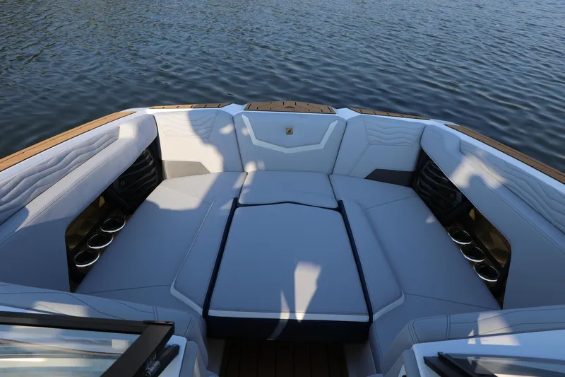 Slide: The Image of 2025 Nautique G25 boat interior with spacious seating and cup holders on a calm lake. - 23