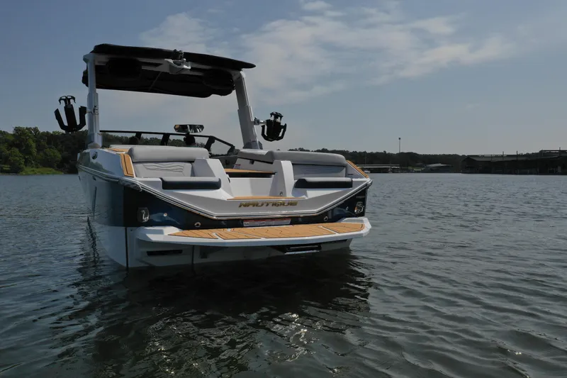 Slide: The Image of 2025 Nautique G25 boat on a calm lake under a clear sky. - 3