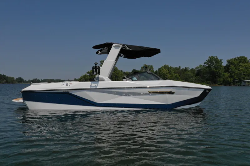 Slide: The Image of 2025 Nautique G25 boat on a calm lake under clear blue sky. - 4