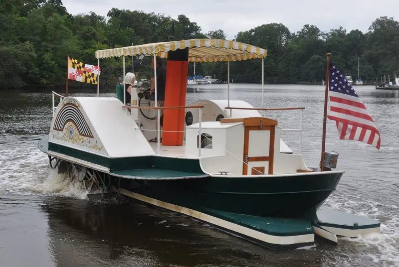 Slide: The Image of Custom 1987 sidewheel paddle yacht cruising on a serene river with flags displayed. - 4