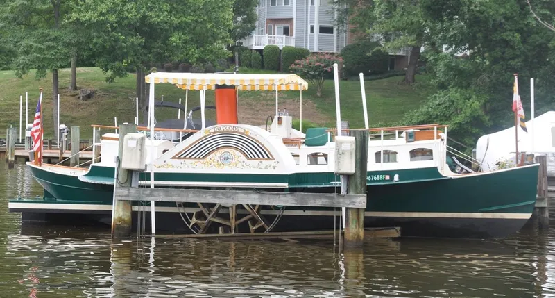 Slide: The Image of Custom 1987 sidewheel paddle yacht docked on a serene river, surrounded by lush greenery. - 8