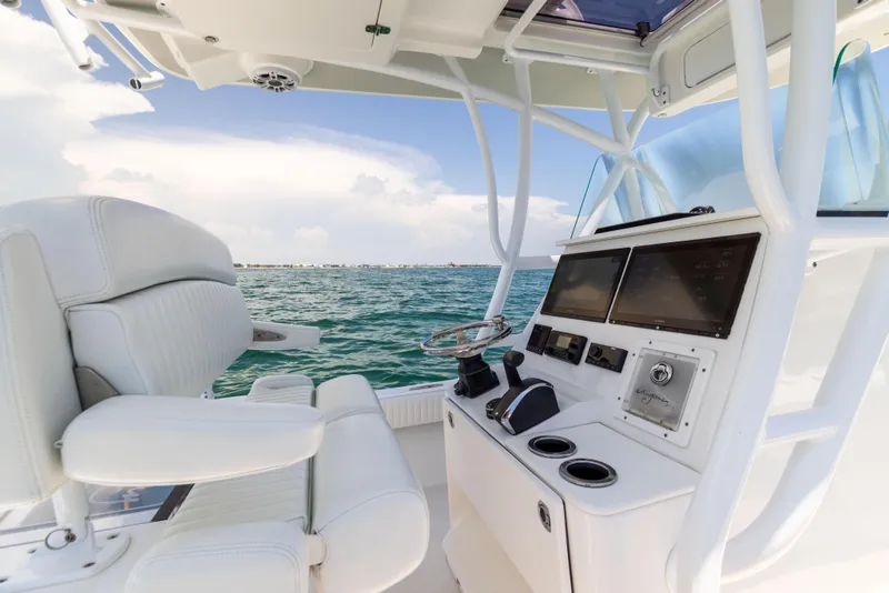 Slide: The Image of Canyon Bay 28h boat interior, 2023 model, featuring modern controls and seating on open water. - 38