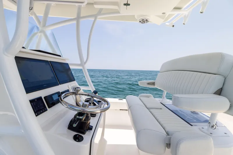 Slide: The Image of 2023 Canyon Bay 28h boat interior with steering wheel and seating, ocean view. - 39