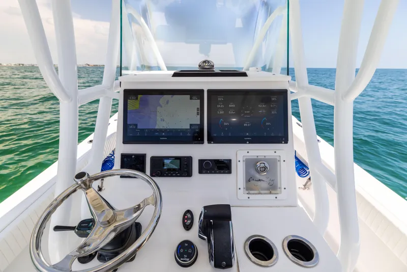 Slide: The Image of 2023 Canyon Bay 28h boat dashboard with navigation screens and steering wheel on open water. - 41