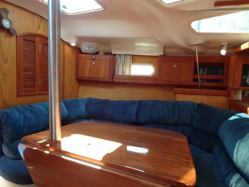 Slide: The Image of Interior of 2001 Hunter 380 sailboat with blue seating and wooden table. - 34