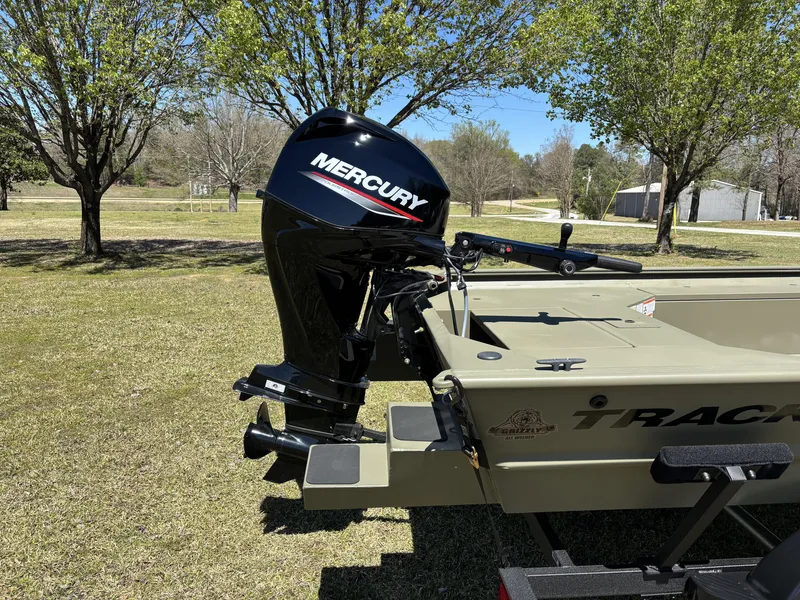Slide: The Image of 2025 Tracker Grizzly 1654 T SportMan boat with Mercury outboard motor in a grassy area. - 11