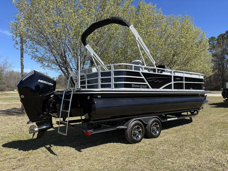 Slide: The Image of 2024 Ranger 223C pontoon boat with Mercury engine on a trailer, parked outdoors. - 2