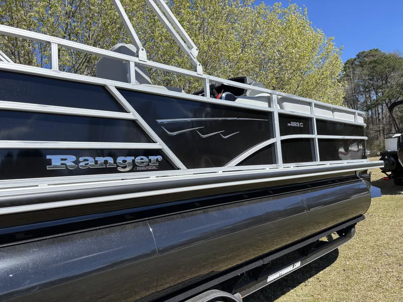 Slide: The Image of 2024 Ranger 223C pontoon boat with sleek black design, parked on grass. - 3