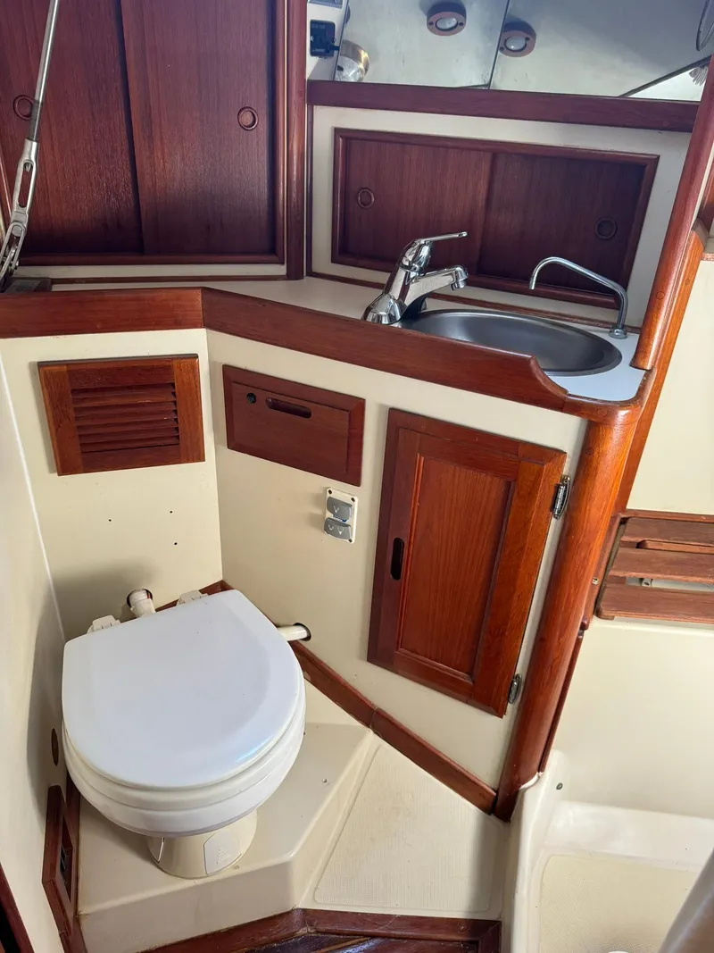 Slide: The Image of 1987 Ericson 35-3 yacht bathroom with sink, toilet, and wooden cabinetry. - 31