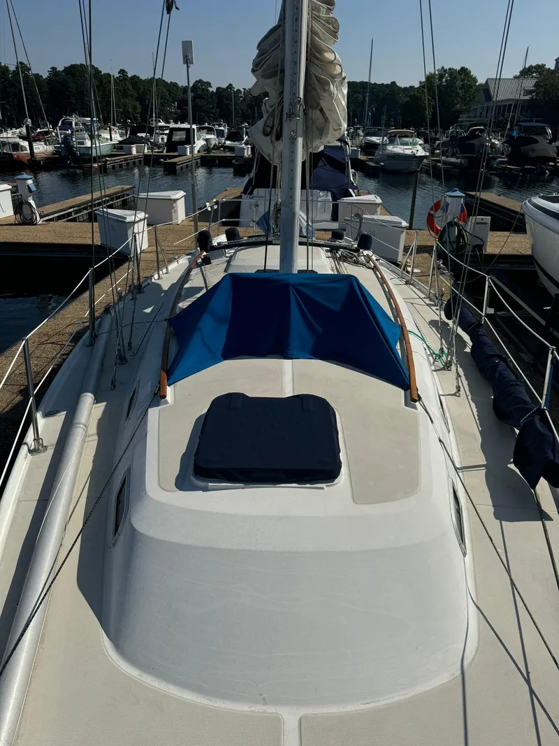Slide: The Image of 1987 Ericson 35-3 sailboat docked at marina, featuring sleek deck and blue cover. - 4