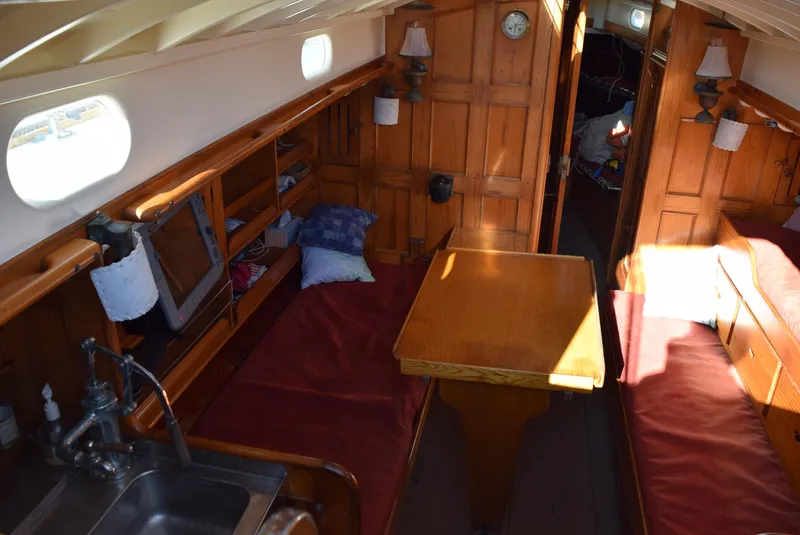 Slide: The Image of Interior of a 1964 Concordia 41 Yawl, featuring wooden paneling and cozy seating. - 18