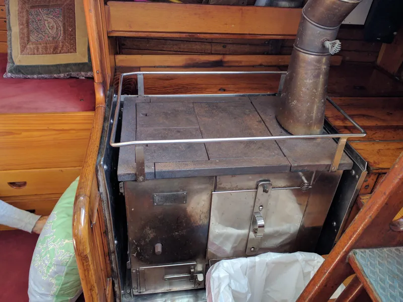 Slide: The Image of Vintage stove inside a 1964 Concordia 41 Yawl, featuring wooden interior and metal chimney. - 22
