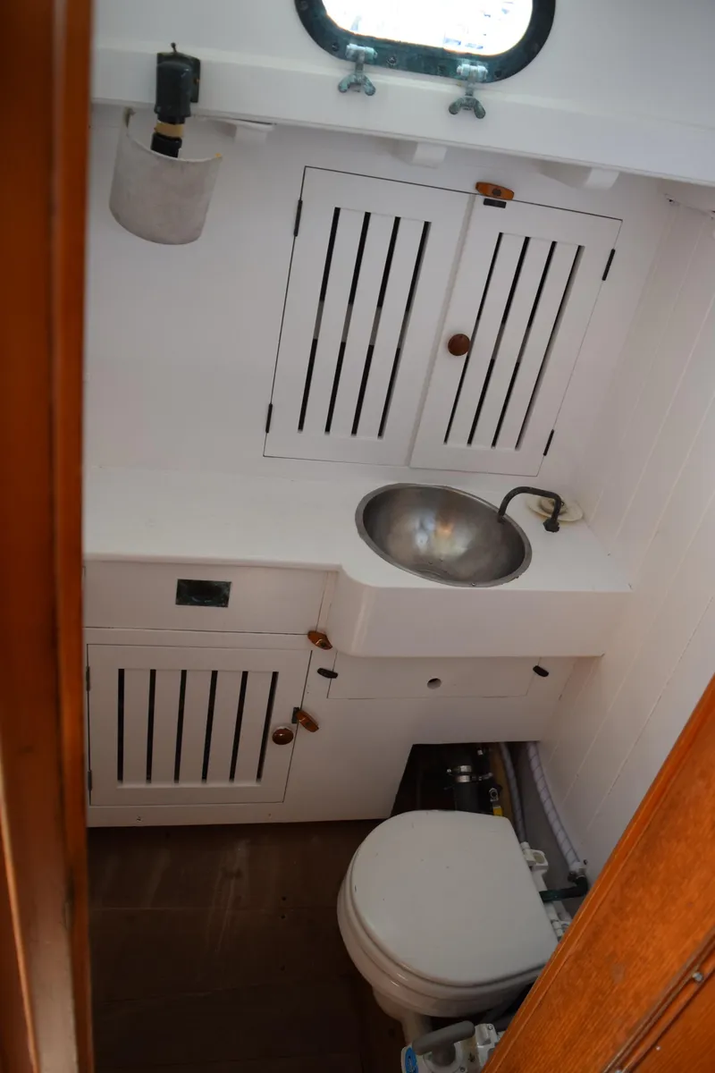 Slide: The Image of Compact bathroom in a 1964 Concordia 41 Yawl, featuring a sink and storage cabinets. - 26
