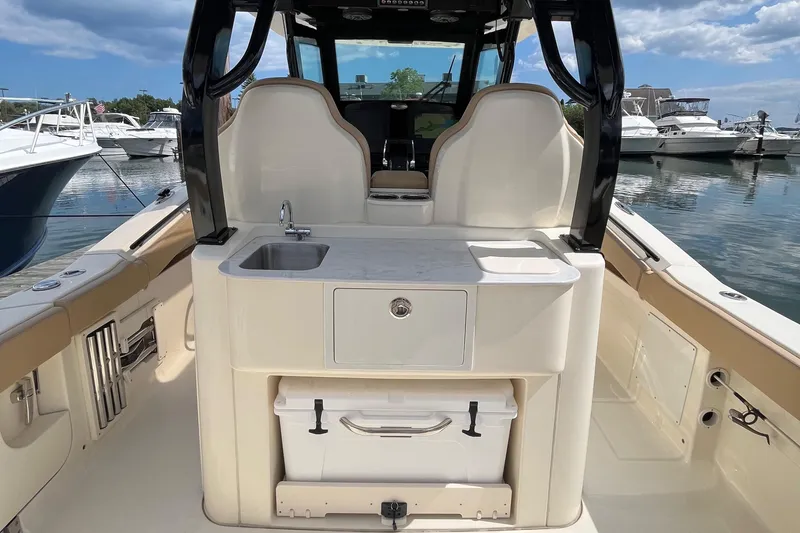 Slide: The Image of 2024 Scout 330 LXF boat interior with sink and storage, docked at marina. - 14