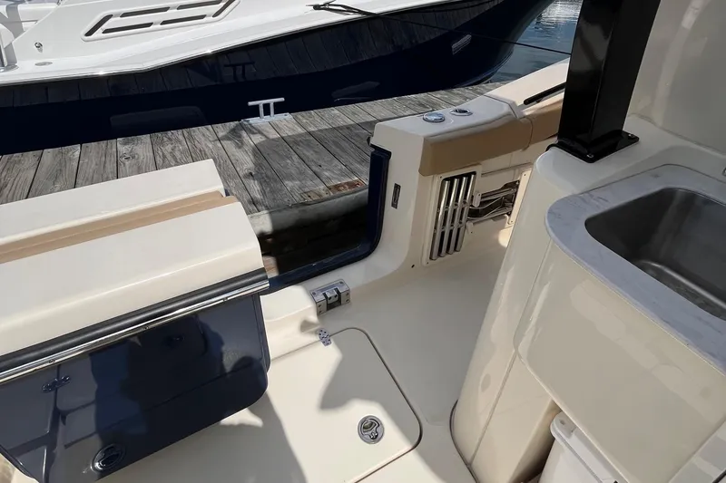 Slide: The Image of 2024 Scout 330 LXF boat interior with seating and sink, docked at marina. - 16
