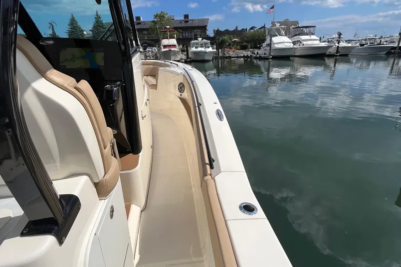 Slide: The Image of 2024 Scout 330 LXF boat docked in a marina with clear skies. - 17