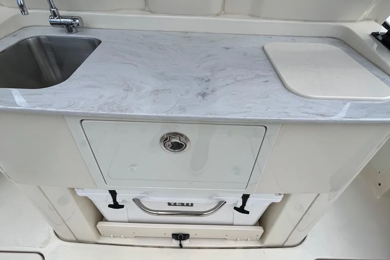 Slide: The Image of 2024 Scout 330 LXF boat kitchen with sink and marble countertop. - 20