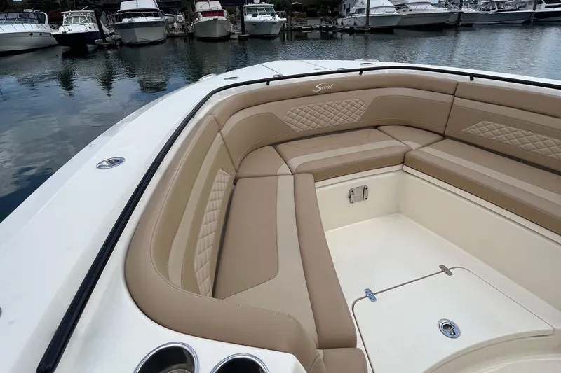 Slide: The Image of 2024 Scout 330 LXF boat with luxurious tan seating in a marina. - 25
