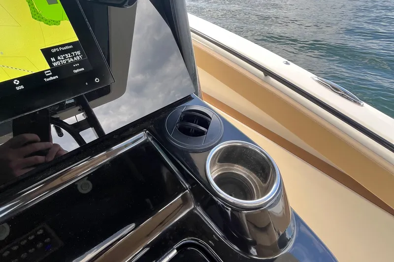 Slide: The Image of 2024 Scout 330 LXF boat console with GPS and cup holder by the water. - 38