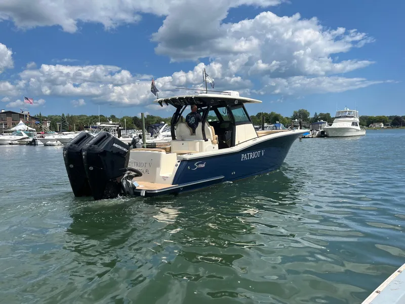 Slide: The Image of 2024 Scout 330 LXF boat on water, clear sky, marina background. - 4