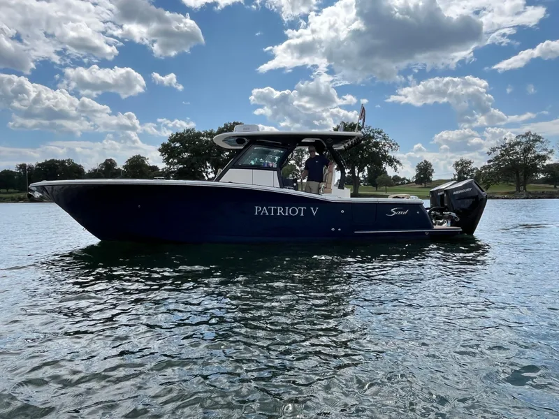 Slide: The Image of 2024 Scout 330 LXF boat on water under blue sky. - 5